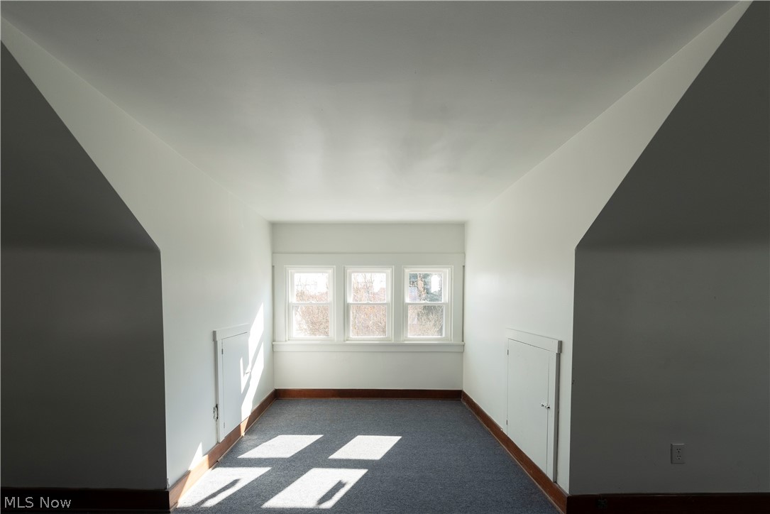 1022 North Howard Street Akron, OH 44310 - Photo 27 of 38 another shot of 3rd floor bedroom. Section with 3 windows flanked by storage access doors with dark colored carpet