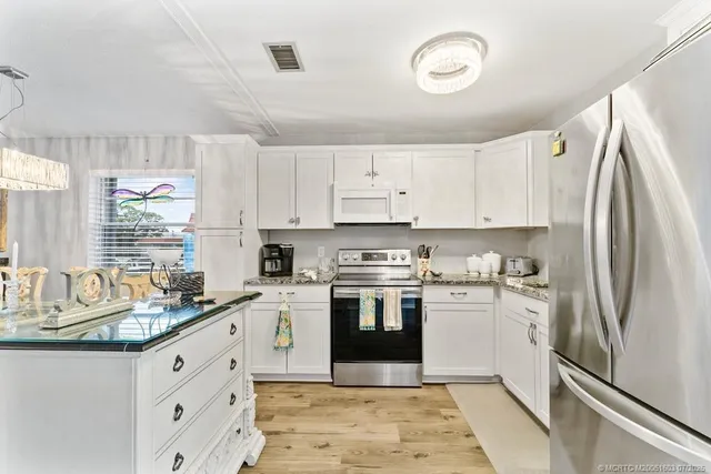 a kitchen with granite countertop a refrigerator stove top oven and sink
