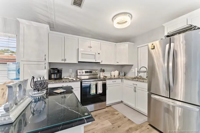 a kitchen with granite countertop a refrigerator stove top oven and sink