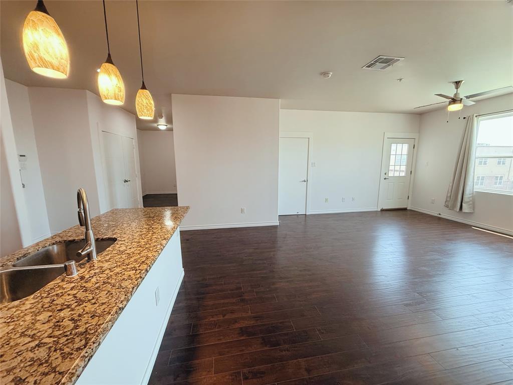 1100 West Trinity Mills Road, Unit 4042 Carrollton, TX 75006 - Photo 11 of 19 Kitchen with dark wood-type flooring, ceiling fan, hanging light fixtures, and light stone counters