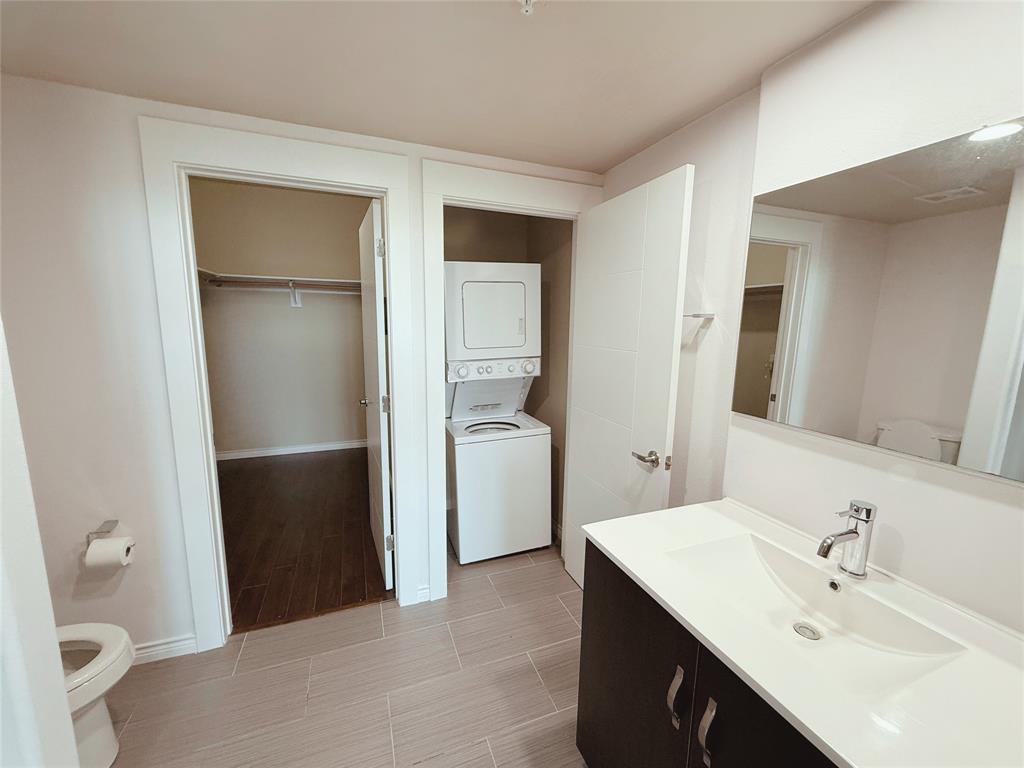 1100 West Trinity Mills Road, Unit 4042 Carrollton, TX 75006 - Photo 15 of 19 Bathroom with stacked washer / dryer, vanity, and a spacious closet