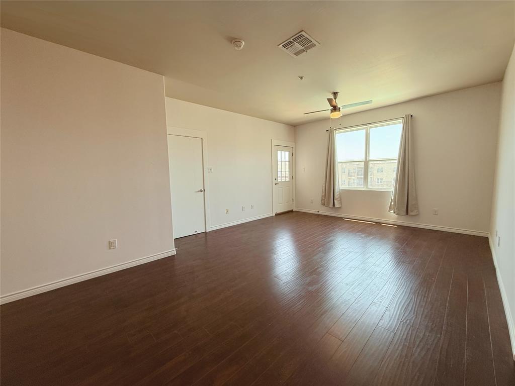 1100 West Trinity Mills Road, Unit 4042 Carrollton, TX 75006 - Photo 3 of 19 Spare room with ceiling fan, a smoke detector, and dark wood finished floors