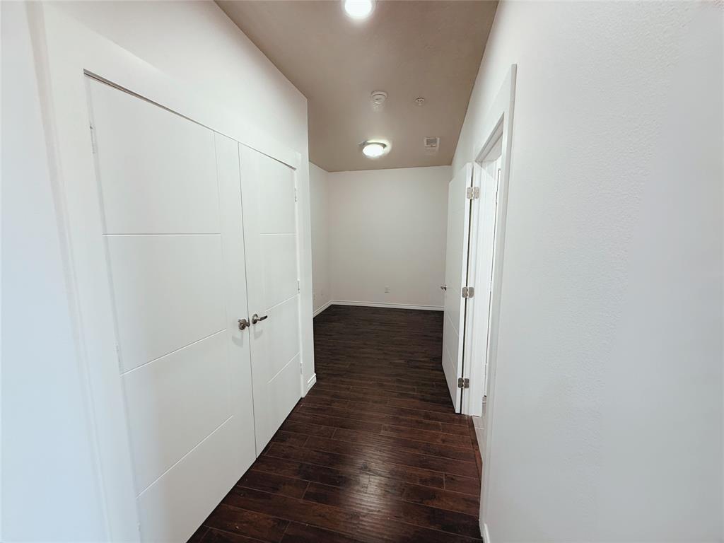 1100 West Trinity Mills Road, Unit 4042 Carrollton, TX 75006 - Photo 4 of 19 Corridor with dark wood-style flooring and baseboards