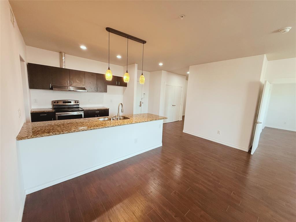 1100 West Trinity Mills Road, Unit 4042 Carrollton, TX 75006 - Photo 10 of 19 Kitchen with electric range, range hood, dark wood-style flooring, recessed lighting, and light stone countertops