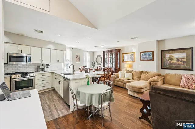 a living room with stainless steel appliances furniture and a kitchen view