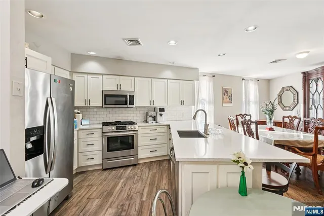 a open kitchen with stainless steel appliances granite countertop a stove refrigerator and a refrigerator with wooden floor