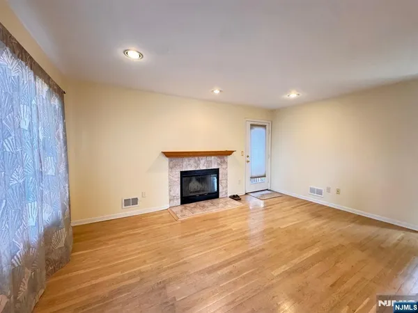 an empty room with wooden floor fireplace and windows