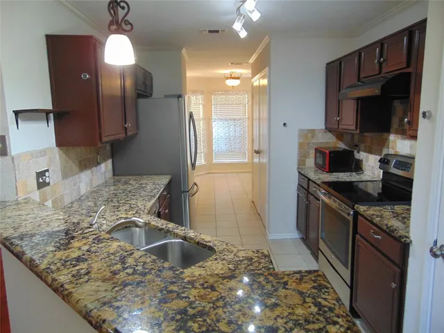 a kitchen with stainless steel appliances granite countertop a sink a stove and a refrigerator
