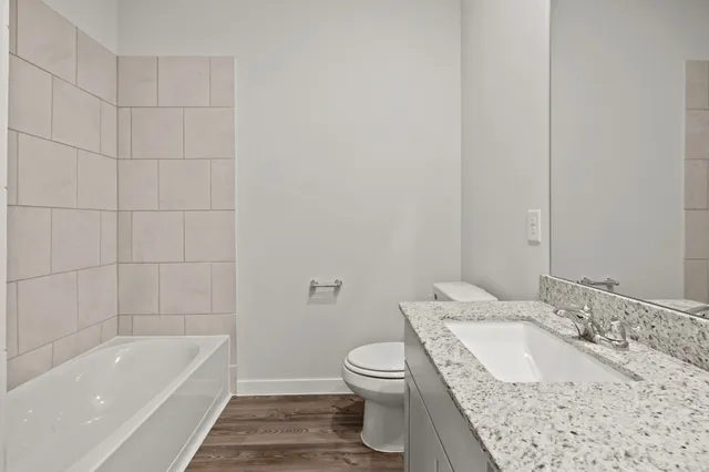 a bathroom with a granite countertop sink a toilet and bathtub