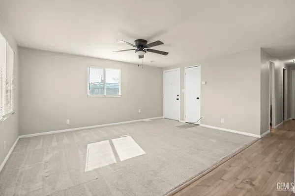 an empty room with chandelier fan and windows