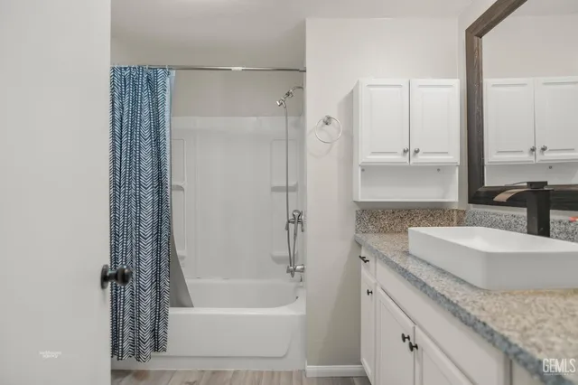 a bathroom with a granite countertop sink a mirror and a bathtub