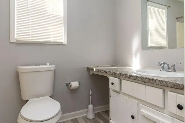 a bathroom with a granite countertop toilet sink and mirror