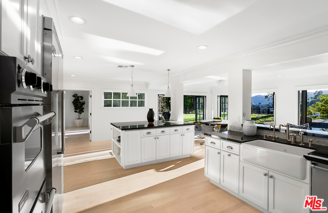 9653 Wendover Drive Beverly Hills, CA 90210 - Photo 19 of 34 a large white kitchen with stainless steel appliances kitchen island granite countertop a large counter top couches and white cabinets