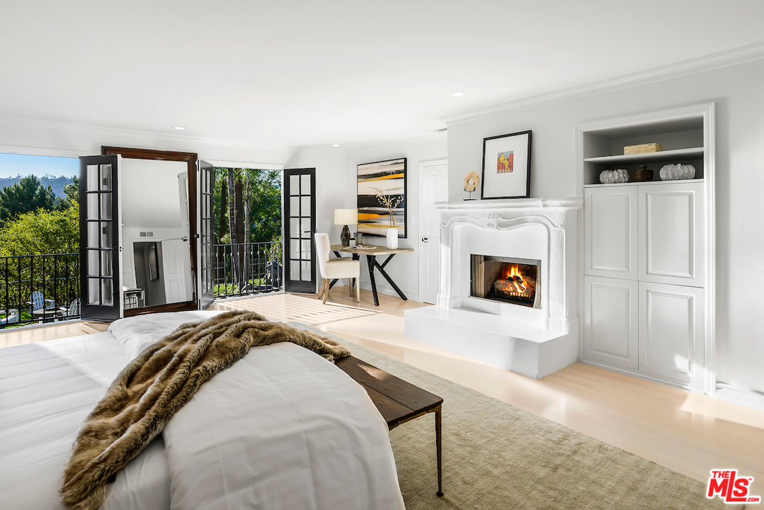 9653 Wendover Drive Beverly Hills, CA 90210 - Photo 26 of 34 a spacious bedroom with a bed a fireplace and a large window with outer view