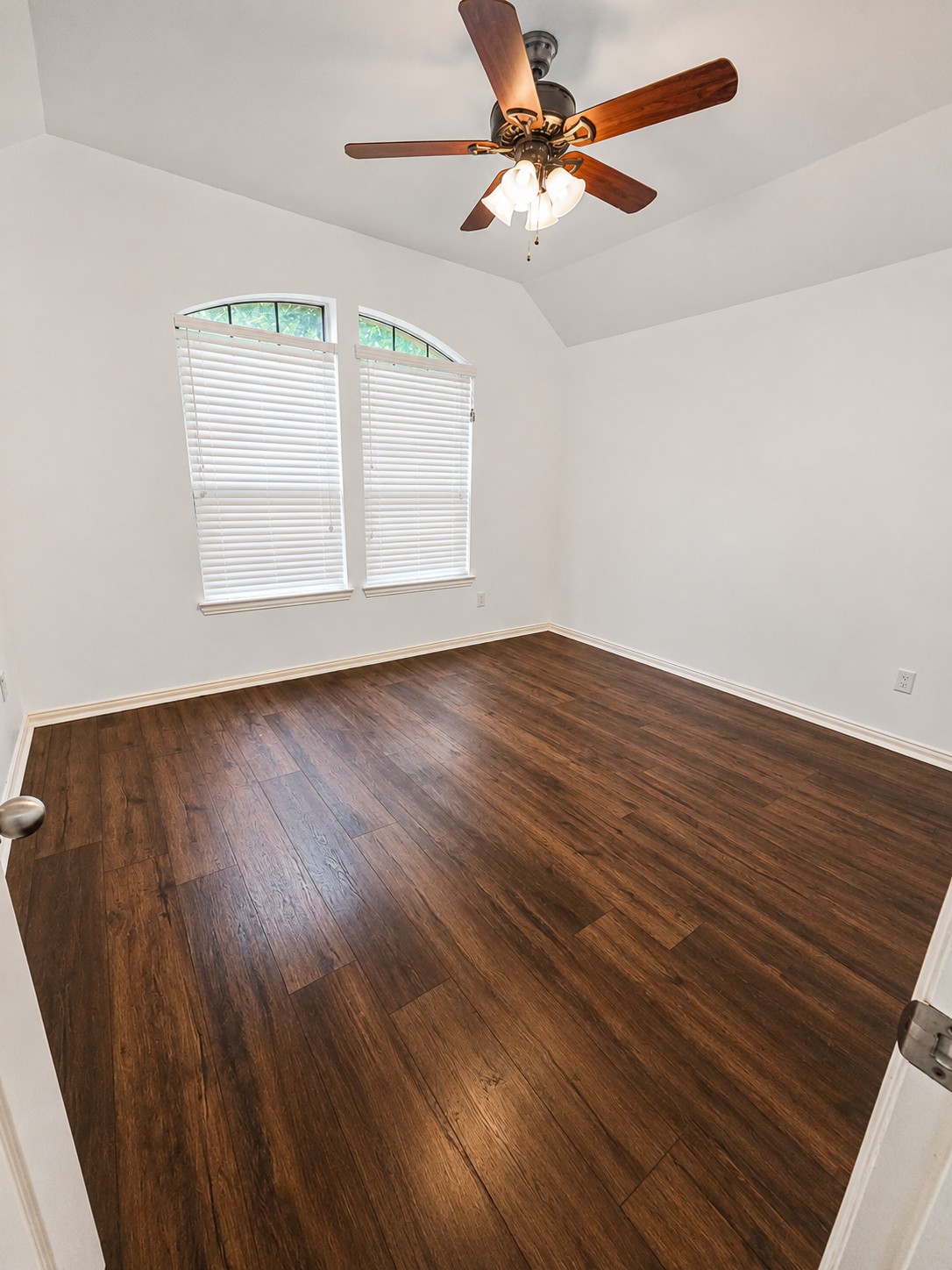 349 Razzmatazz Trail Buda, TX 78610 - Photo 9 of 27 Rich wood flooring grounds this airy room, highlighted by arched windows and a ceiling fan.