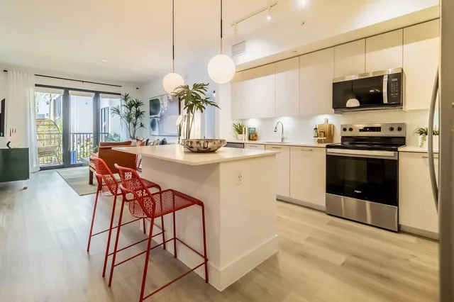 a kitchen with stainless steel appliances granite countertop a stove top oven a sink dishwasher a dining table and chairs with wooden floor