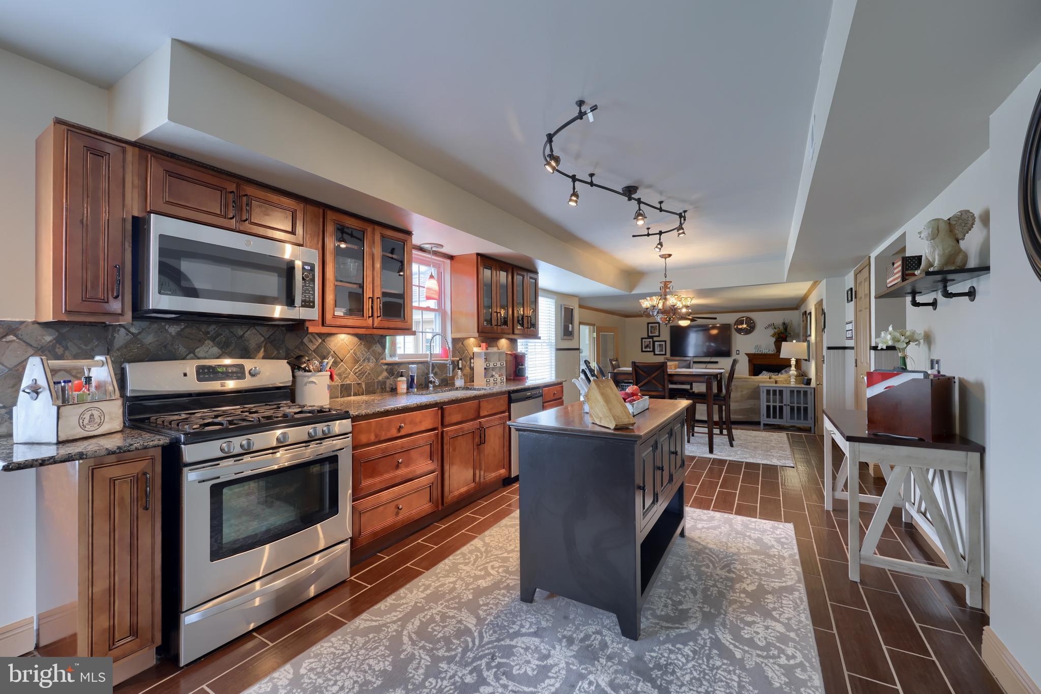 100 Roxberry Drive Reading, PA 19608 - Photo 14 of 46 a kitchen with stainless steel appliances granite countertop a stove top oven a sink dishwasher a dining table and chairs with wooden floor