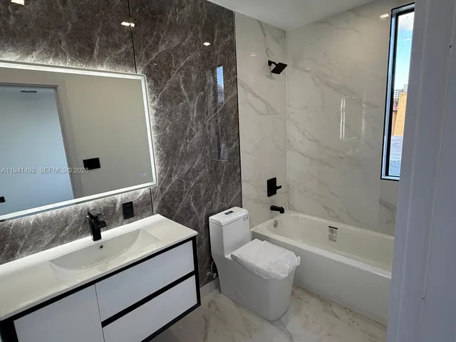 a bathroom with a bathtub shower sink vanity and toilet