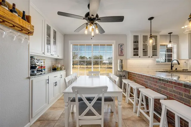 a very nice looking kitchen with granite countertop a stove and white cabinets