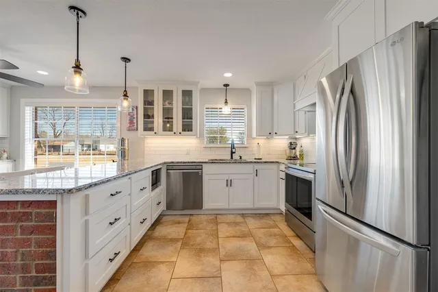 a large kitchen with stainless steel appliances granite countertop a refrigerator and a sink