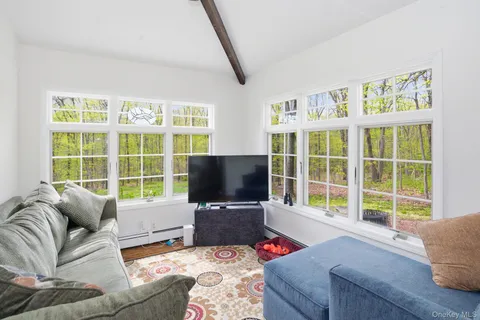 a living room with furniture a flat screen tv and a floor to ceiling window