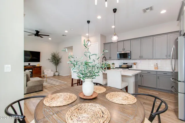 a kitchen with stainless steel appliances granite countertop a refrigerator a stove a microwave oven a sink dishwasher and a dining table with wooden floor