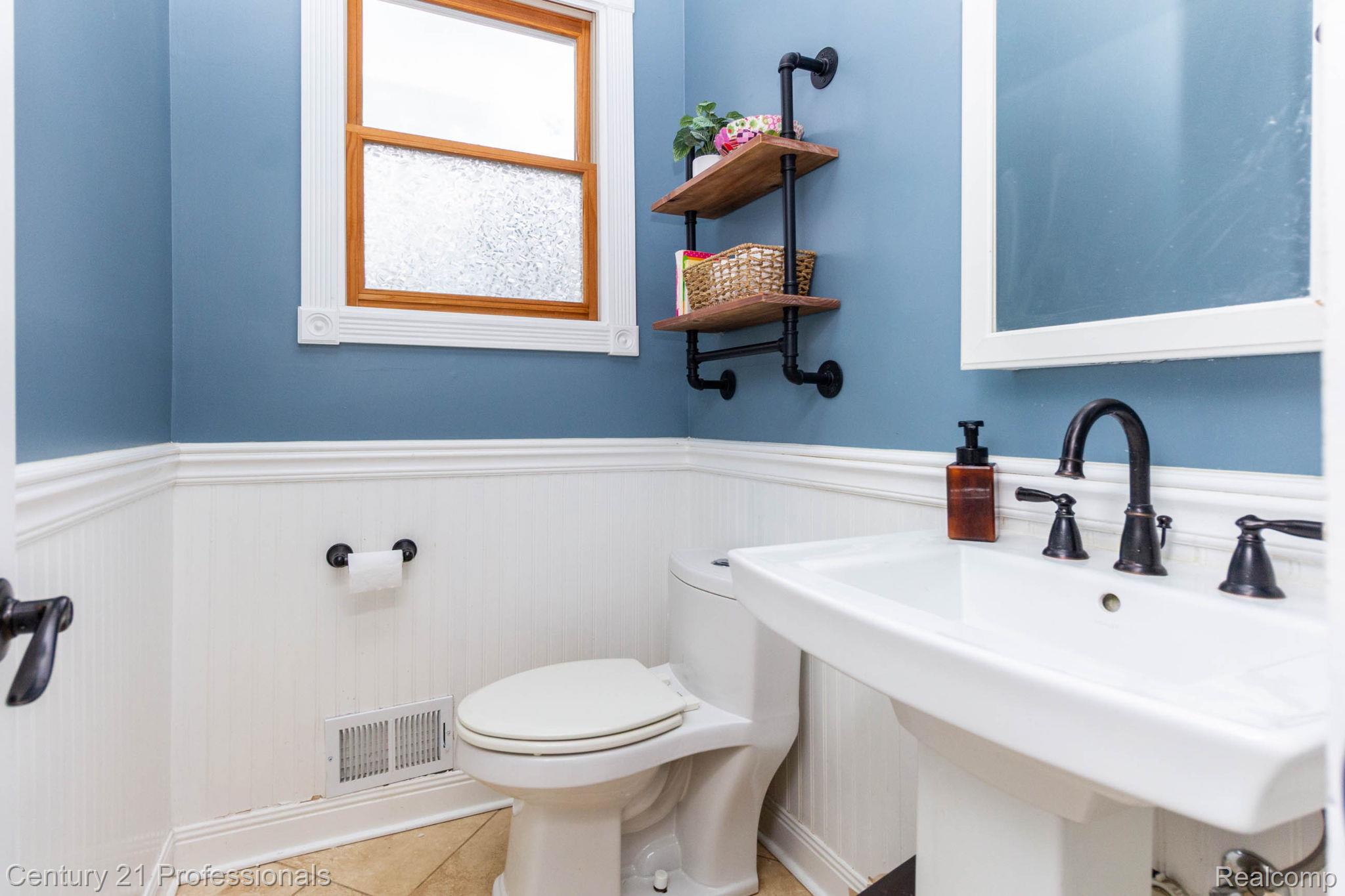 671 Bridgestone Drive Rochester, MI 48309 - Photo 35 of 50 Pedestal sink with black faucet fixtures, white beadboard wainscoting, and a window with a wood frame