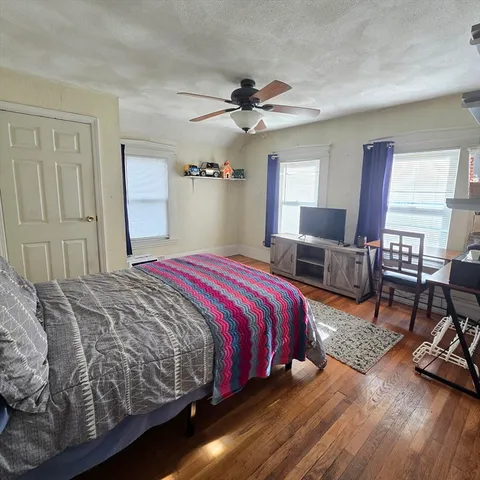 a bedroom with a bed a couch and dresser next to a window