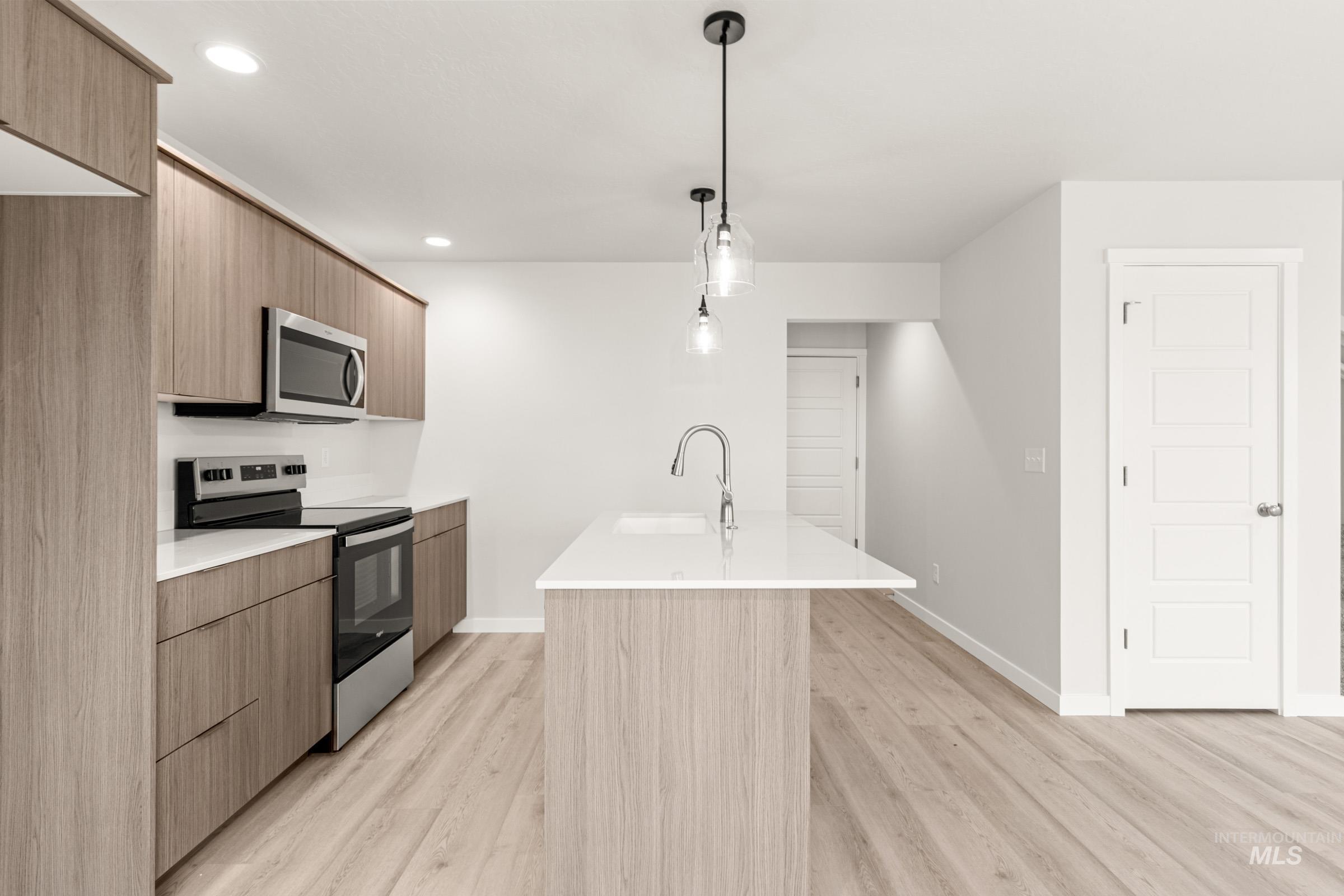 10832 Rutland Street Caldwell, ID 83605 - Photo 4 of 20 Kitchen with an island with sink, stainless steel appliances, modern cabinets, pendant lighting, and light wood-style floors