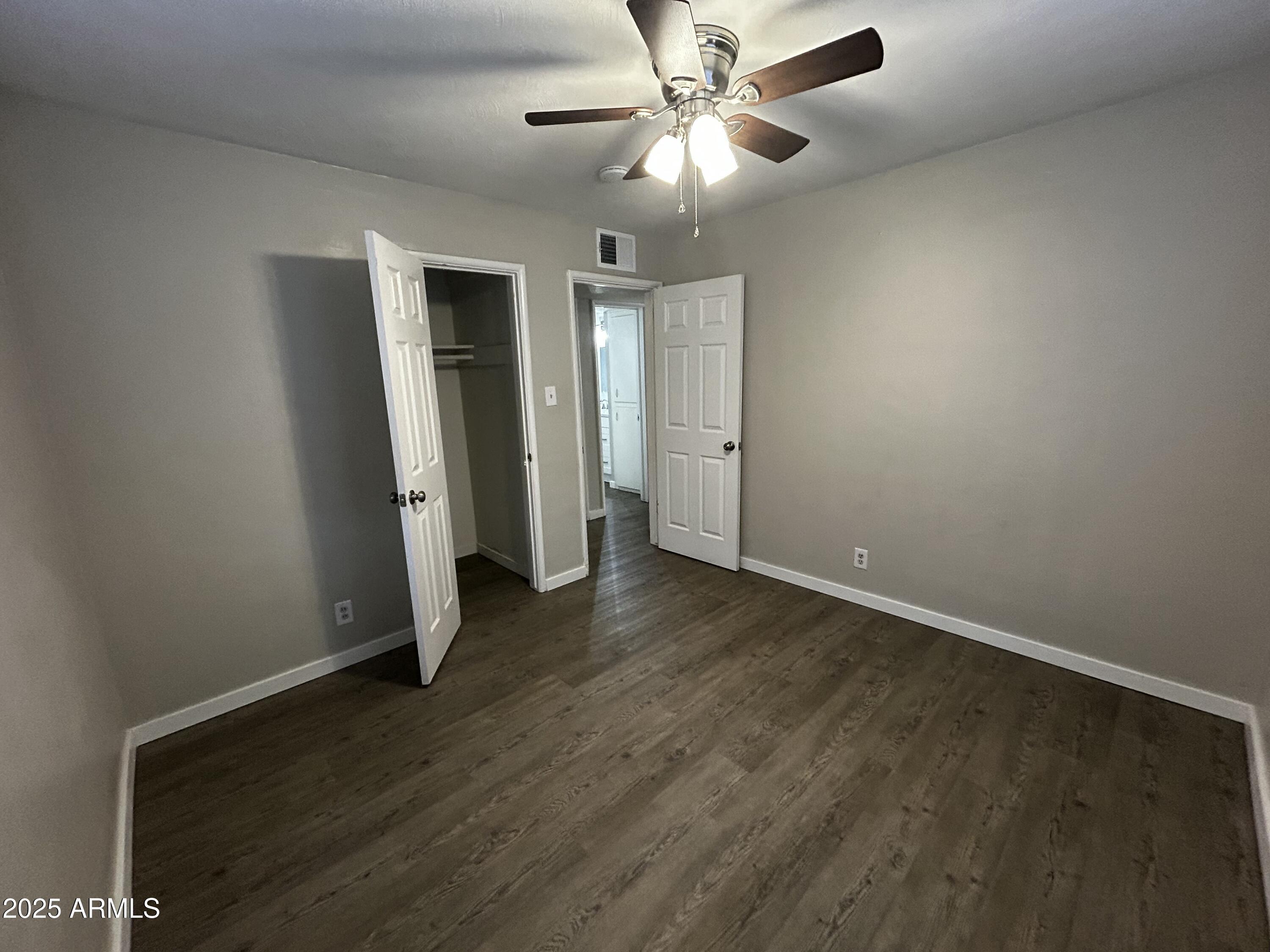 2811 North 17th Place Phoenix, AZ 85006 - Photo 11 of 28 an empty room with wooden floor chandelier fan and closet area
