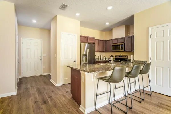 a kitchen with kitchen island granite countertop wooden floors and stainless steel appliances