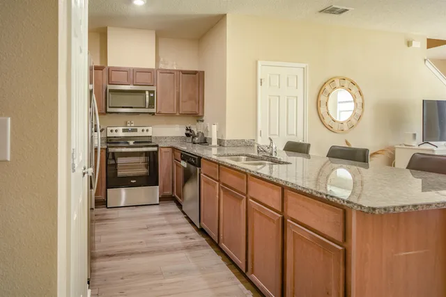 a large kitchen with stainless steel appliances granite countertop a sink a stove and a refrigerator