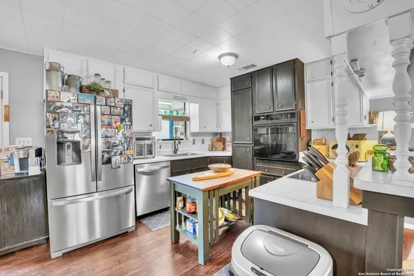 a kitchen with stainless steel appliances a refrigerator a sink a stove and white cabinets