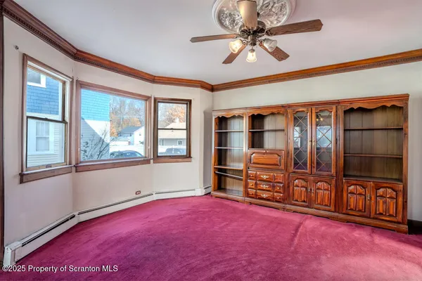 an empty room with windows cabinet and a ceiling fan