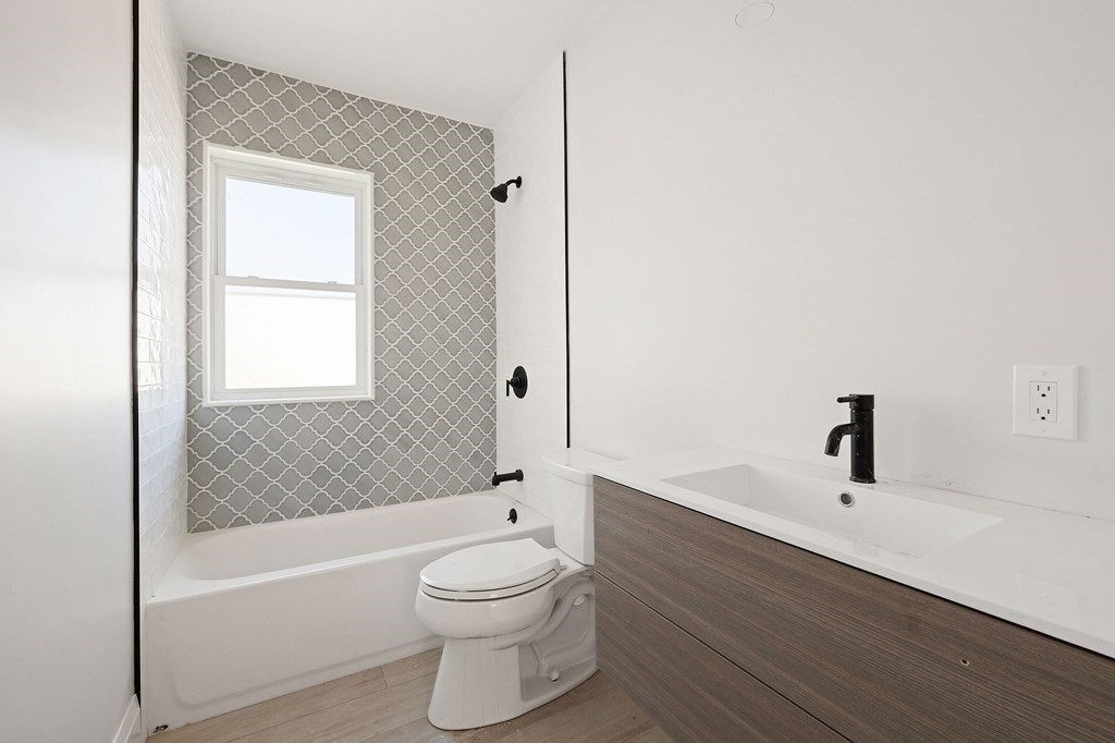 849 Cummins Highway, Unit 3 Boston, MA 02126 - Photo 5 of 7 a bathroom with a bathtub shower sink vanity and toilet