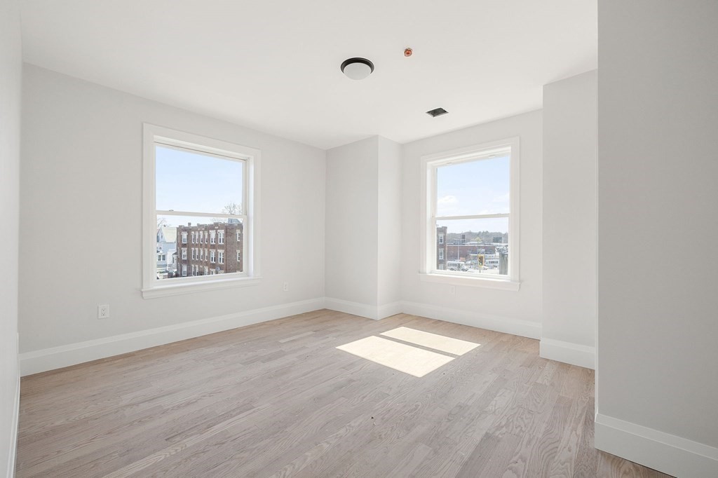 849 Cummins Highway, Unit 3 Boston, MA 02126 - Photo 6 of 7 an empty room with wooden floor and windows