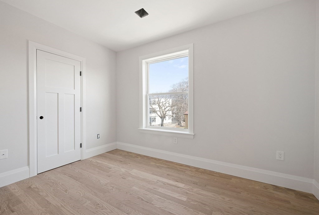 849 Cummins Highway, Unit 3 Boston, MA 02126 - Photo 7 of 7 an empty room with wooden floor and windows