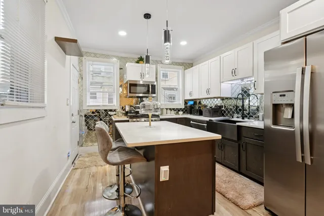 a kitchen with kitchen island a refrigerator a stove a sink and chairs