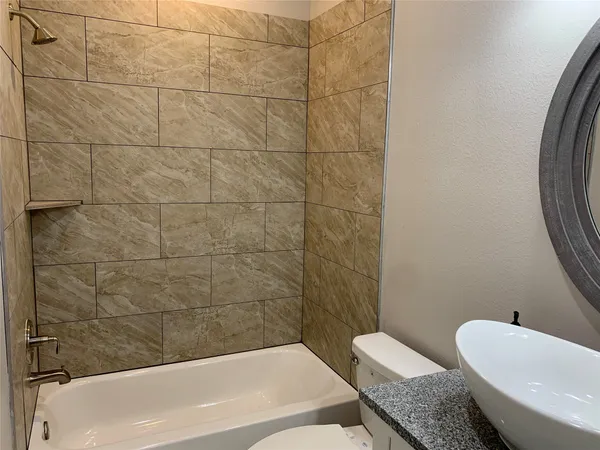 a bathroom with a granite countertop sink and a bathtub