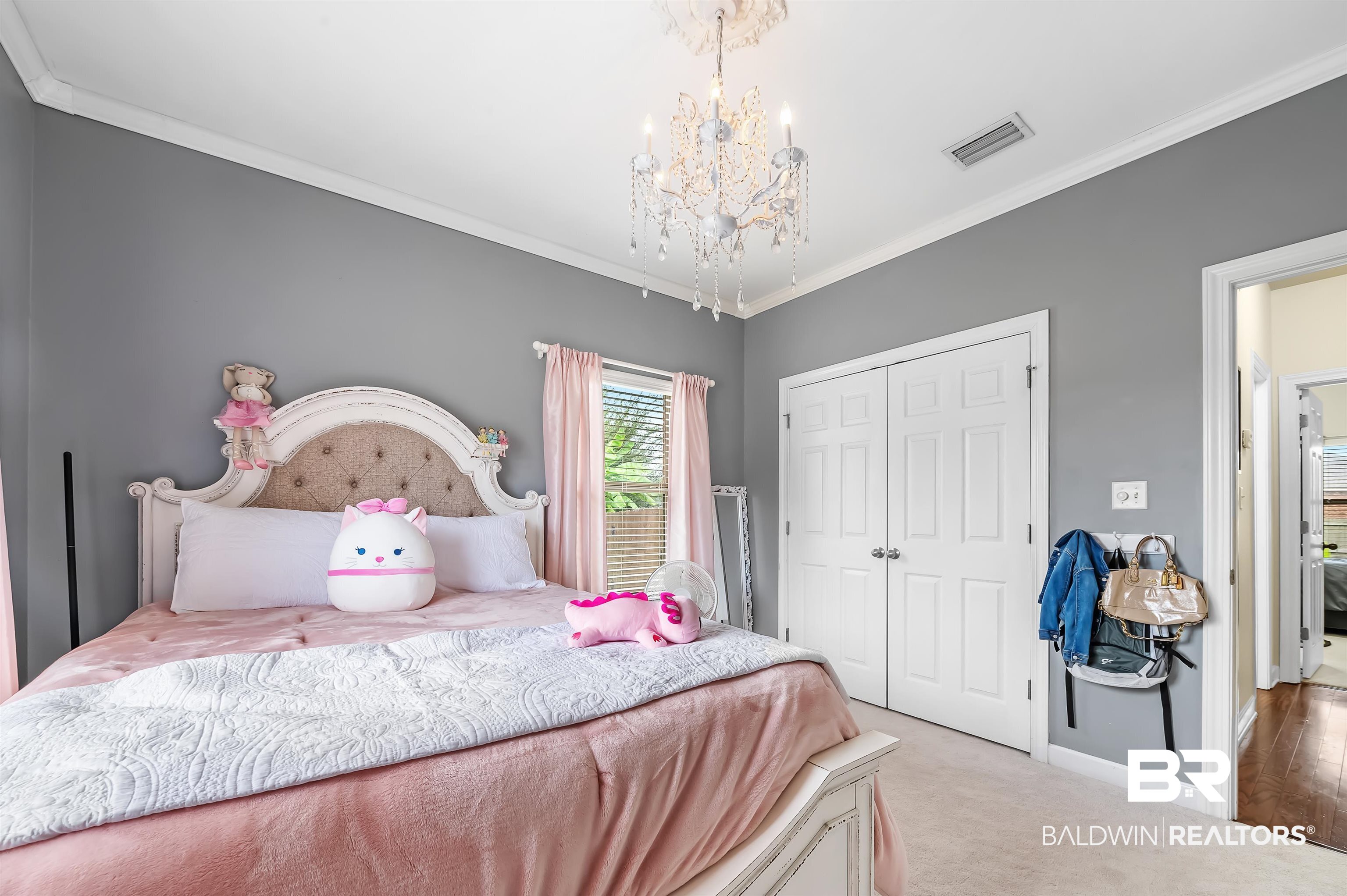 9376 Sable Court Daphne, AL 36526 - Photo 29 of 46 Bedroom with light carpet, a closet, a notable chandelier, and crown molding