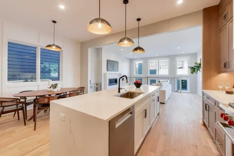 a large kitchen with kitchen island a stove a counter a sink a dining table and chairs