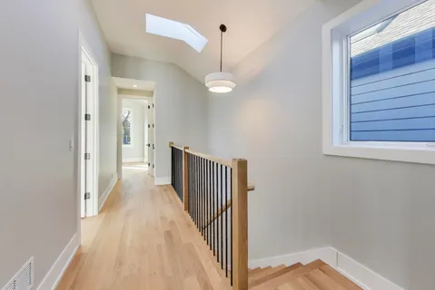 a view of a hallway with wooden floor and staircase