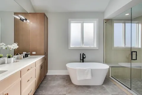 a bathroom with a double vanity sink mirror and bathtub