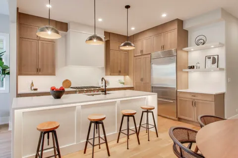 a kitchen with stainless steel appliances kitchen island a table chairs refrigerator and sink