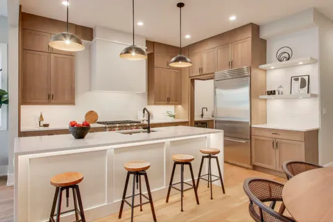 a kitchen with stainless steel appliances kitchen island a table chairs in it and wooden floors