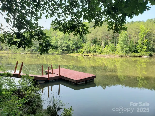 a view of a lake with lawn chairs and large trees