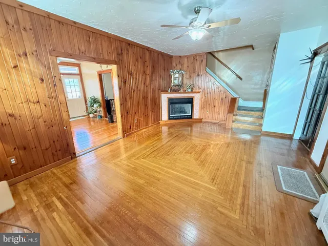 a view of a livingroom with wooden floor and a ceiling fan