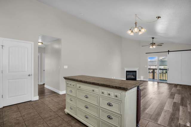 1836 West 800 North Mapleton, UT 84663 - Photo 9 of 38 Kitchen featuring dark countertops, vaulted ceiling, ceiling fan, a glass covered fireplace, and suspended lighting