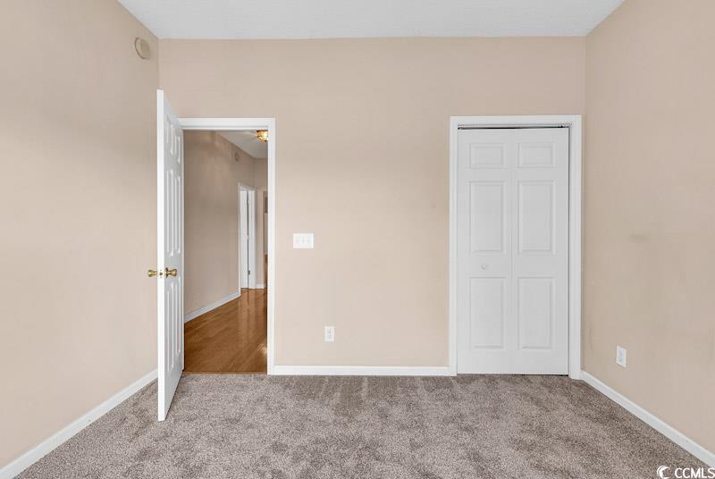 4672 Lightkeepers Way, Unit 50E Little River, SC 29566 - Photo 12 of 19 Unfurnished bedroom featuring light carpet and a closet