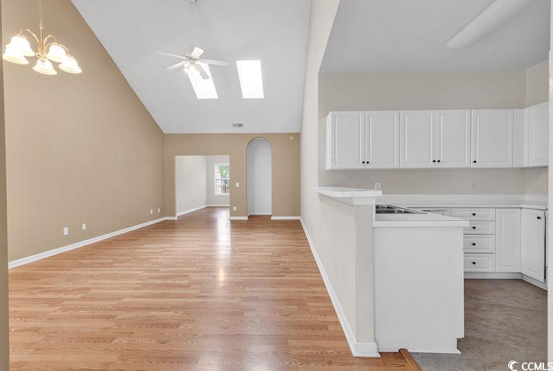 4672 Lightkeepers Way, Unit 50E Little River, SC 29566 - Photo 3 of 19 Kitchen featuring white cabinets, ceiling fan with notable chandelier, a skylight, decorative light fixtures, and light hardwood / wood-style floors